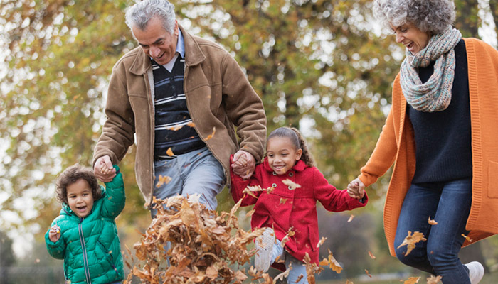 Elderly couple with young children playing in fallen leaves